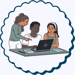 A two students sit at a desk with a laptop, an adult stands beside them helping